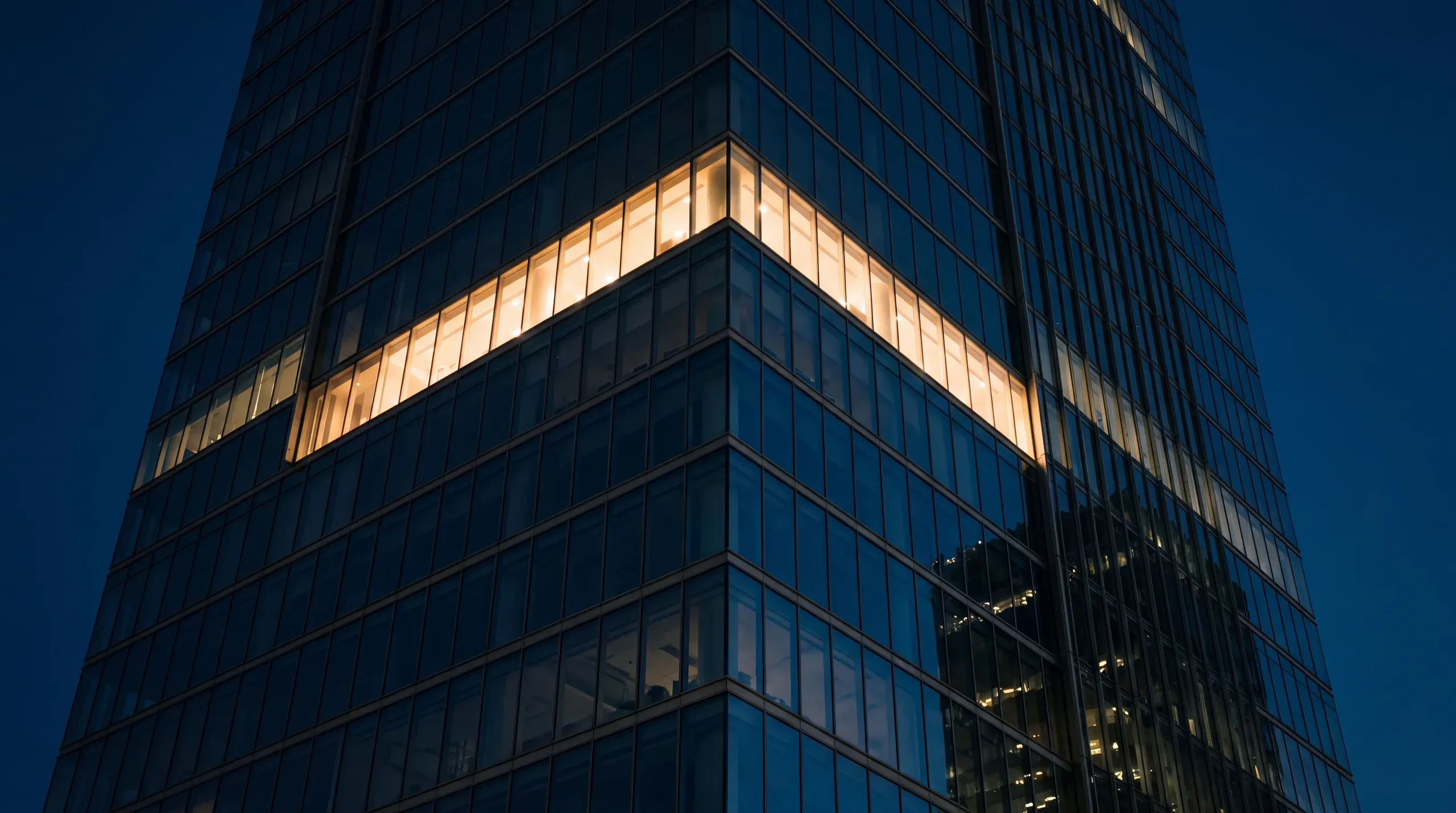 Torre corporativa al anochecer con una planta iluminada